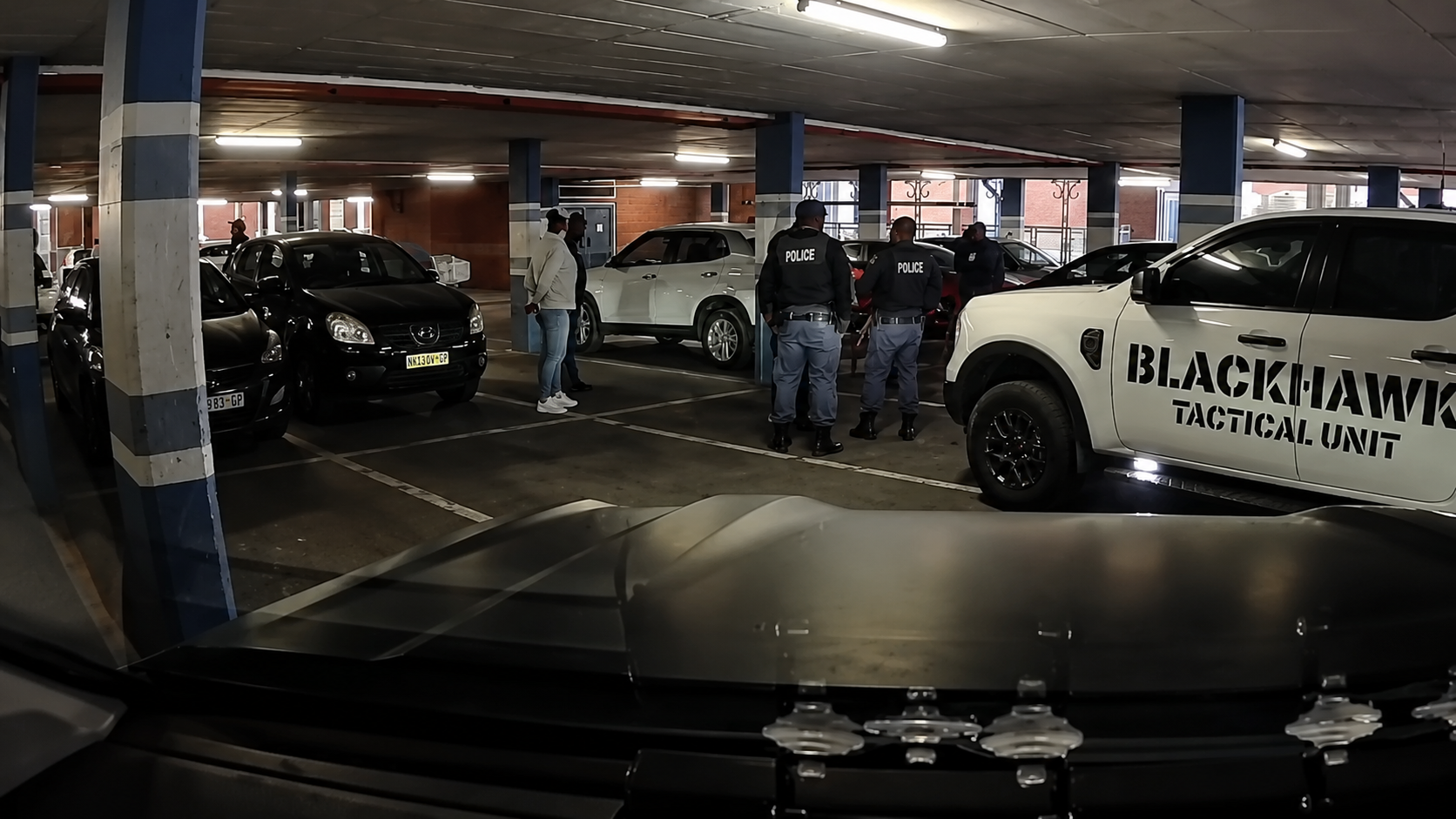 SAPS members and a Blackhawk Tactical Unit vehicle on the Lakeside Mall parking deck during the response